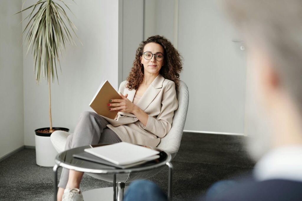 Businesswoman sitting in a modern office with a notebook, exuding professionalism and confidence.